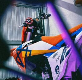 name hgktfnrg9xc d8c94e64 16ed 4d57 a712 ccf8edcc68eb.jpg a colorful dirt bike parked next to a building